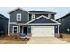 Two-story home with navy blue siding, white garage door, and landscaping at 106 Obadiah Ct, Troutman, NC 28115