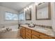 Well-lit bathroom showcases a double vanity, granite countertop, and a soaking tub by the window at 3195 Hadden Hall Blvd, Fort Mill, SC 29715