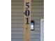 Close-up of a wooden post displaying the house number 501 in blue, along with a lantern-style porch light fixture at 501 Ed Wilson Rd, Bessemer City, NC 28016