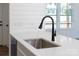Close up on kitchen sink, faucet, and quartz countertop with shiplap backsplash and stainless dishwasher at 501 Ed Wilson Rd, Bessemer City, NC 28016