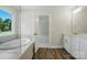 Bright bathroom features a soaking tub by a window and a vanity with white cabinets at 5112 Heathland Dr # 75, Charlotte, NC 28215