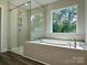 Modern bathroom with a soaking tub and glass-enclosed shower, plus large windows at 5112 Heathland Dr # 75, Charlotte, NC 28215