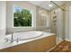 Modern bathroom featuring a soaking tub, a window overlooking greenery, and a glass-enclosed shower at 5115 Heathland Dr # 47, Charlotte, NC 28215