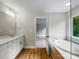Bright bathroom with a double vanity, soaking tub, walk-in shower, and wood-look flooring at 5115 Heathland Dr # 47, Charlotte, NC 28215