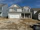 Charming two-story home with stone accents, gray siding, and a two-car garage on a sunny day at 5115 Heathland Dr # 47, Charlotte, NC 28215