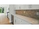 A kitchen with white cabinets, stone countertops, stainless steel appliances, and natural stone backsplash at 5115 Heathland Dr # 47, Charlotte, NC 28215