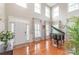 Bright living room features high ceilings, large windows, hardwood floors, and a grand piano at 8905 Valleymoon Ln, Charlotte, NC 28214