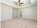 Generous primary bedroom showcasing a tray ceiling, ceiling fan, ensuite bath and natural light at 149 Halite Ln, Waxhaw, NC 28173