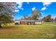 Charming brick single-story home featuring a well-maintained lawn and mature trees under a beautiful blue sky at 4501 Taylorsville Hwy, Statesville, NC 28625