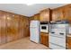 Kitchen featuring wood cabinets, white appliances, and wood paneling at 4501 Taylorsville Hwy, Statesville, NC 28625