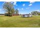 Large grassy yard with mature trees and outbuildings under a blue sky, offering space and potential at 4501 Taylorsville Hwy, Statesville, NC 28625