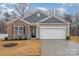 Charming single-Gathering home with stone accents, manicured lawn, and two-car garage at 654 Saddlebred Ln, Locust, NC 28097