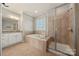 Well-lit bathroom featuring a soaking tub, glass shower, and double vanity for a luxurious bathing experience at 13929 Tilesford Ln, Huntersville, NC 28078