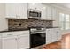 Close-up of the kitchen featuring stainless steel appliances and stylish backsplash at 13929 Tilesford Ln, Huntersville, NC 28078