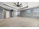 Spacious main bedroom featuring neutral carpet, gray walls, large windows, and a ceiling fan at 13929 Tilesford Ln, Huntersville, NC 28078