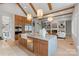 Open-concept kitchen with marble countertops, island with seating, wood beam accents, and stainless steel appliances at 407 Crepe Myrtle Ln, Weddington, NC 28104
