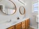 Bathroom featuring a double sink vanity with wood cabinets, dual round mirrors, and a window at 8225 Ballymore Ct, Huntersville, NC 28078