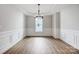 A formal dining room featuring hardwood floors, white wainscotting, tray ceiling, and a modern light fixture at 4021 Grace Pointe Dr # 104, Wesley Chapel, NC 28079