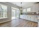 Bright eat-in kitchen with an outdoor view, white cabinets, stone backsplash, and hardwood floors at 4021 Grace Pointe Dr # 104, Wesley Chapel, NC 28079