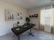 Cozy, carpeted home office space with a modern desk and soft natural lighting from a window at 1602 Village Grove Ln, Monroe, NC 28110