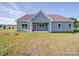 Rear exterior view of the light blue home with covered patio, and level yard at 220 W Lawyers Rd, Monroe, NC 28110