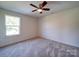 Bedroom featuring soft carpet, a ceiling fan and a window overlooking outside greenery at 220 W Lawyers Rd, Monroe, NC 28110