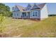 Angled view of the blue house showing front porch and manicured landscaping at 220 W Lawyers Rd, Monroe, NC 28110
