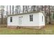 Small white single-wide home with stone base, nestled in a wooded setting at 100 Steffey Ln, Taylorsville, NC 28681