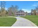 Inviting home features a circular driveway and a charming front porch, set against a backdrop of lush greenery at 12300 Caldwell Rd, Charlotte, NC 28213