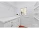 The laundry room is an all-white space with built-in shelves and cabinets and a window that lets in natural light at 12300 Caldwell Rd, Charlotte, NC 28213