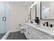 Modern bathroom featuring double sinks, white cabinetry, and a glass-enclosed shower at 2201 Catalina Ave, Charlotte, NC 28206