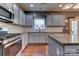 Well-lit kitchen features stainless steel appliances, granite countertops, and stylish grey cabinets at 3848 Burnage Hall Rd, Harrisburg, NC 28075