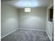 Clean, carpeted room with a contemporary light fixture, neutral walls, and a pass-through to the kitchen at 6017 Treetop Ct, Charlotte, NC 28212