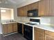 Well-lit kitchen featuring wood cabinets, laminate countertops, black appliances, and wood-style flooring at 6017 Treetop Ct, Charlotte, NC 28212