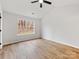 Bright bedroom with a ceiling fan, wood-look floors, and a large window overlooking a wooded area at 10519 Brawley Ln, Charlotte, NC 28215