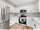 Kitchen showcasing stainless steel appliances, white cabinets, and countertops with a mosaic backsplash at 10519 Brawley Ln, Charlotte, NC 28215