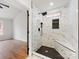 Modern shower with a bench, black hardware, shower niche, and large marble-look tiles at 10519 Brawley Ln, Charlotte, NC 28215