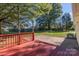 Red wooden deck with railing, opening to a patio and large backyard with mature trees at 2216 Lowell Bethesda Rd, Gastonia, NC 28056