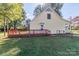 Rear view of a yellow home with a red deck, fenced yard, and a peaceful outdoor space at 2216 Lowell Bethesda Rd, Gastonia, NC 28056