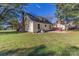 Spacious, grassy backyard view of a yellow home with a brick chimney and a red back deck at 2216 Lowell Bethesda Rd, Gastonia, NC 28056
