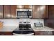 Close up of stainless steel stove top and microwave with dark wood cabinets and granite countertops at 280 Kerri Dawn Ln, Locust, NC 28097