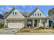 Beige two-story house with a three-car garage and manicured lawn at 14535 Crosswater Ln, Charlotte, NC 28278