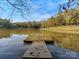 Picturesque pond view with a wooden dock extending into the water, surrounded by fall foliage and a gazebo at 294 Carroll Cv, Clover, SC 29710