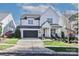 Charming two-story white farmhouse with a black garage door, manicured lawn, and inviting front porch at 12023 Huntson Reserve Rd, Huntersville, NC 28078