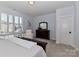 A bed sits in front of a dresser with a mirror, as well as a white arm chair in this main bedroom at 12023 Huntson Reserve Rd, Huntersville, NC 28078