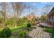 Picturesque backyard with brick-paved path, wooden deck, and mature trees at 7943 Oratorio Pl, Charlotte, NC 28270