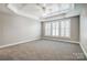 A Primary bedroom with carpet floors, a tray ceiling, a ceiling fan, and plantation shutters at 7943 Oratorio Pl, Charlotte, NC 28270