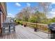 A rear wooden deck featuring a grill, chairs, plants and a view into the back yard at 7943 Oratorio Pl, Charlotte, NC 28270