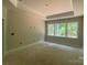 Bright, unfinished bedroom with a tray ceiling and large windows overlooking greenery at 9130 Dulwich Dr # Ken0079, Charlotte, NC 28215
