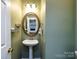 Small powder room with pedestal sink and oval mirror at 1801 Brandywine Dr, Matthews, NC 28105